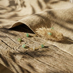 Elegancka bransoletka z naturalnym zielonym awenturynem i złotym łańcuszkiem na rustykalnym tle.